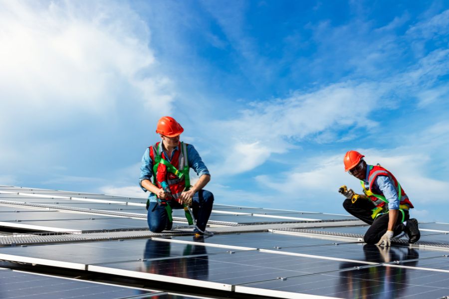 Worker installing solar panels on large roof