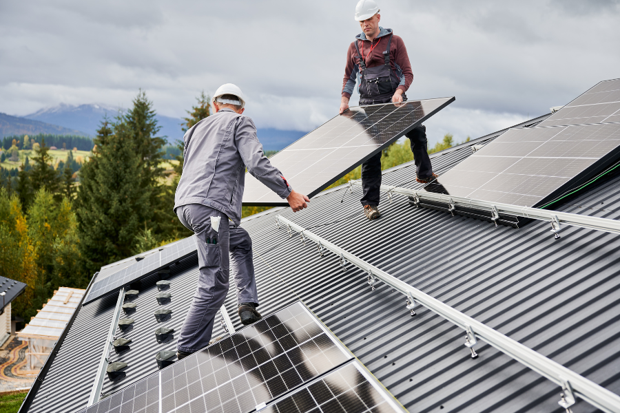 Professionals carrying solar panels on house roof