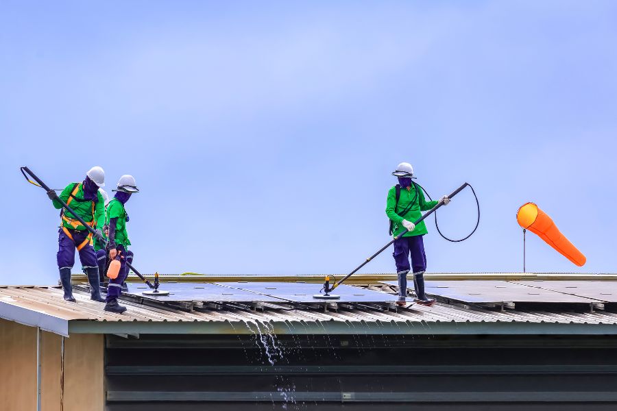 Group of professionals cleaning solar panels on the roof