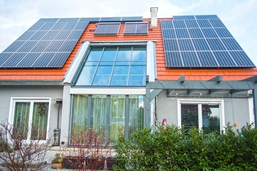 House with solar panels and solar thermal collectors on roof