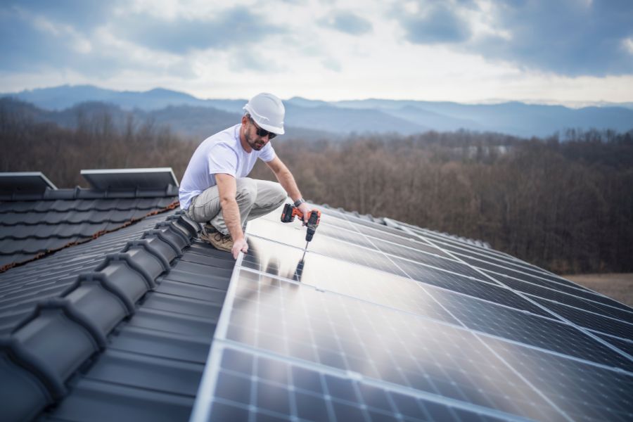 Professional installing solar panels on roof of a modern house
