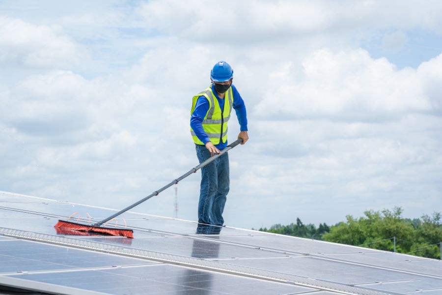 Worker cleaning solar panel on the roof