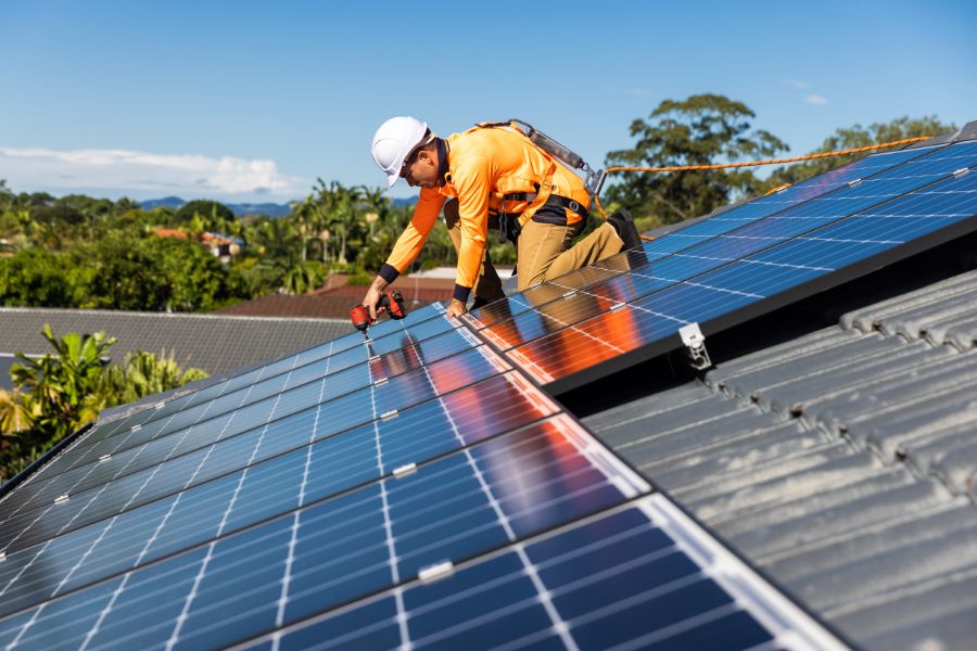 Technician installing solar panels on house roof