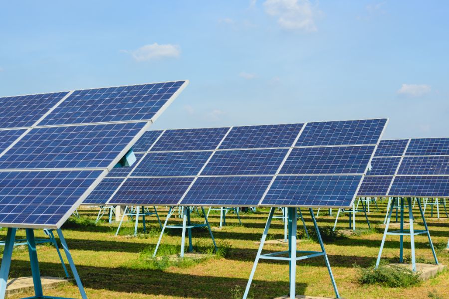 Rows of solar panels with sun at solar farm